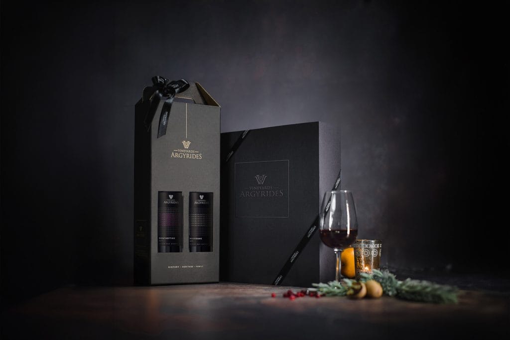 Argyrides Vineyards premium two-bottle gift box with Maratheftiko and Mourvedre, a black branded gift box, a glass of red wine, and seasonal decorations