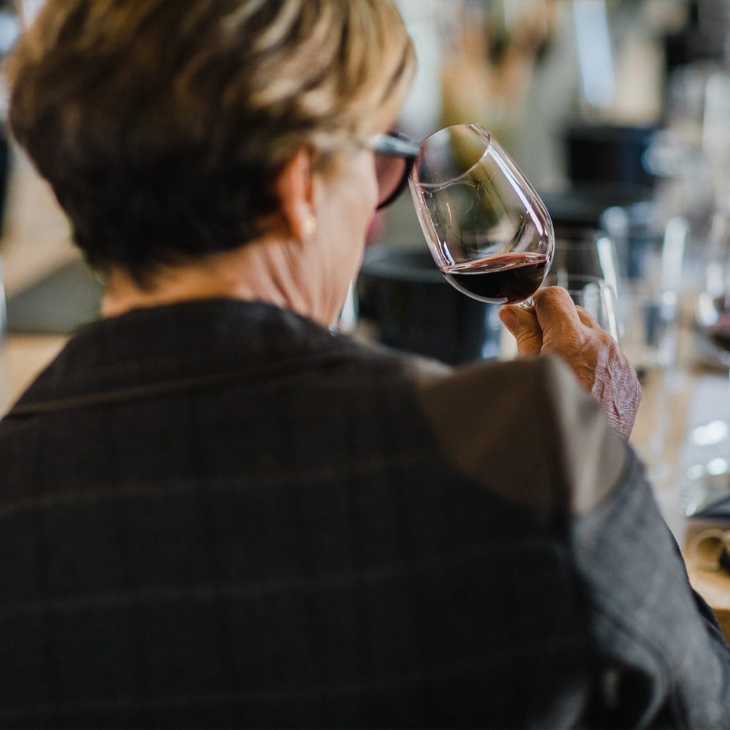 Woman holding a glass of red wine and examining its colour during a wine tasting at Argyrides Winery